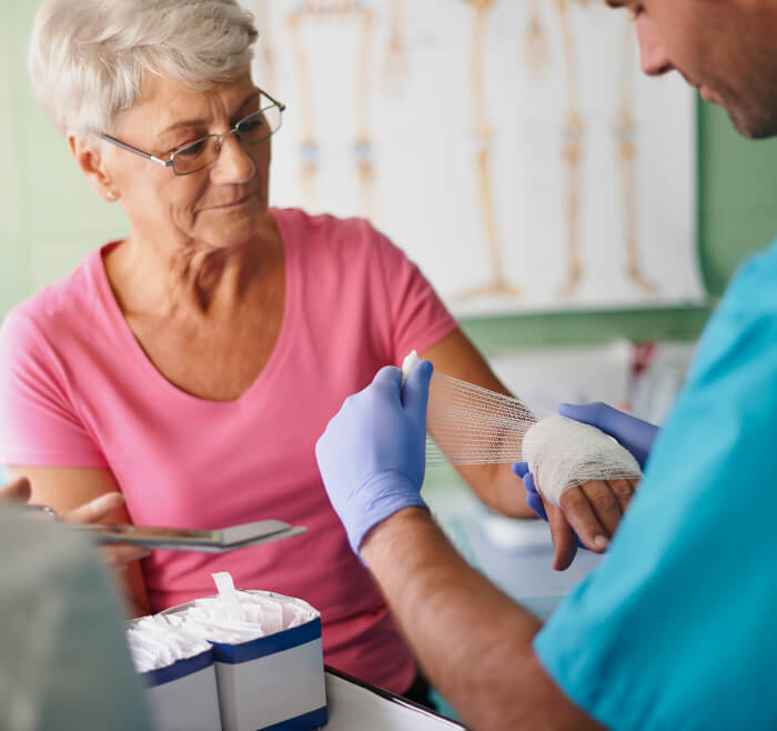 An older woman being dressed her hand by medical professional